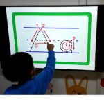 A boy traces the letter A to learn the correct alphabet stroke order.