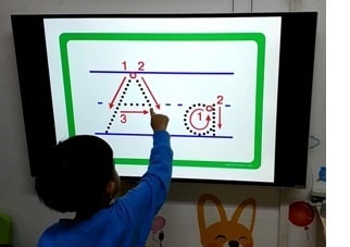 A boy traces the letter A to learn the correct alphabet stroke order.